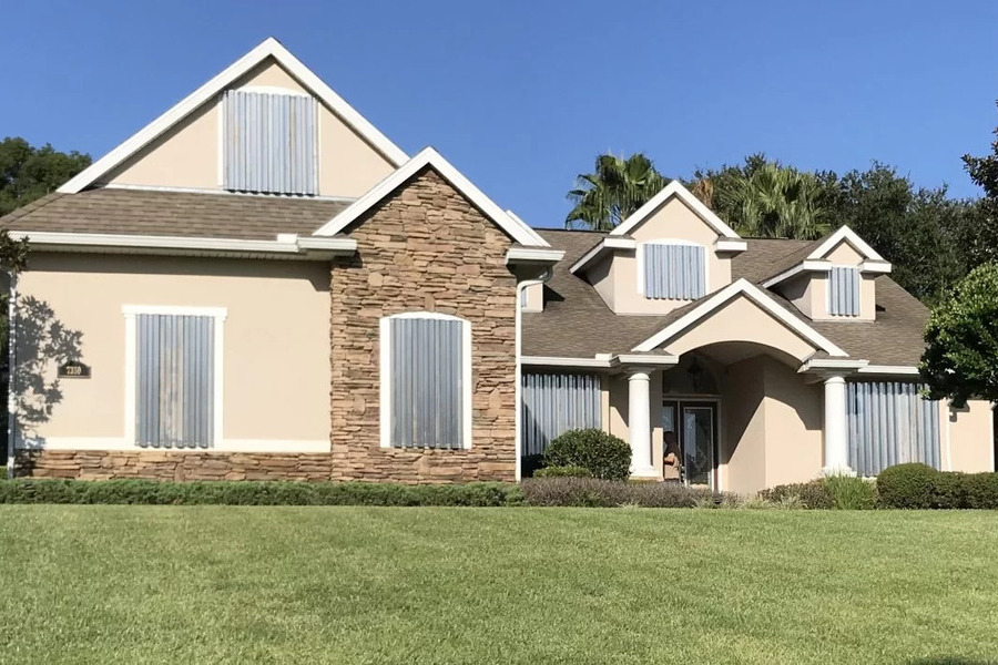 Workers installing accordion storm shutters on a Florida home exterior